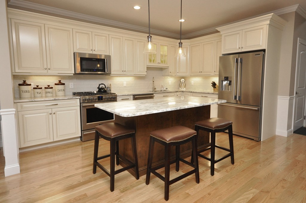 a kitchen with stainless steel appliances granite countertop a table chairs microwave and refrigerator