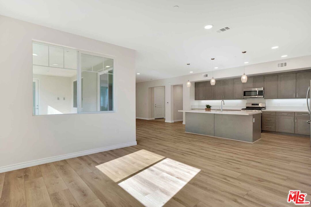 2850 Wagon Wheel Road, Unit 401 Oxnard, CA 93036 - Photo 13 of 31 a large white kitchen with kitchen island a stove a sink dishwasher and a refrigerator with wooden floor