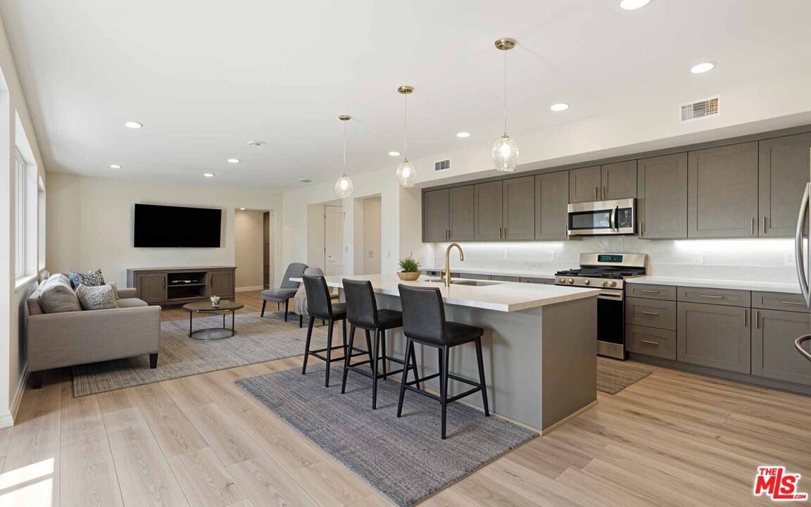 2850 Wagon Wheel Road, Unit 401 Oxnard, CA 93036 - Photo 2 of 31 a kitchen with stainless steel appliances granite countertop a stove top oven a sink dishwasher a dining table and chairs with wooden floor