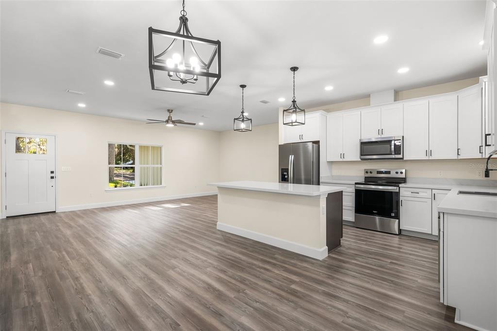 332 Southeast 3rd Avenue Melrose, FL 32666 - Photo 13 of 36 a kitchen with stainless steel appliances a refrigerator a stove oven a sink dishwasher and white cabinets with wooden floor
