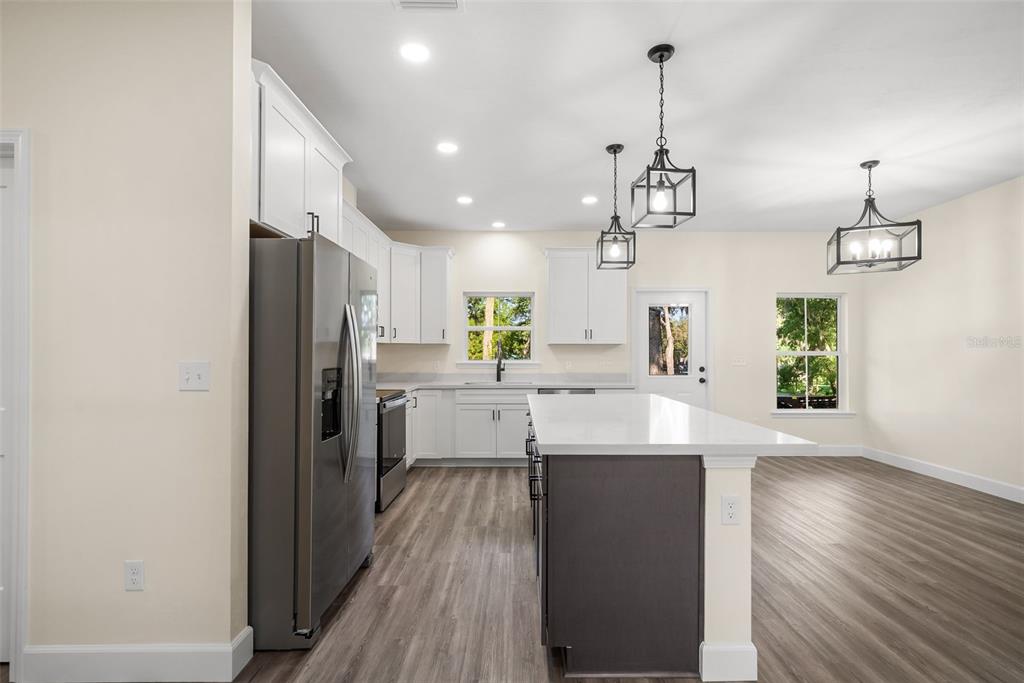 332 Southeast 3rd Avenue Melrose, FL 32666 - Photo 15 of 36 a kitchen with stainless steel appliances kitchen island granite countertop a refrigerator a sink dishwasher a oven and a dining table with wooden floor