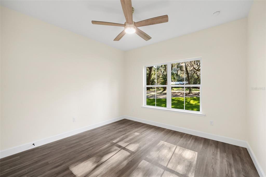 332 Southeast 3rd Avenue Melrose, FL 32666 - Photo 24 of 36 an empty room with wooden floor chandelier fan and windows