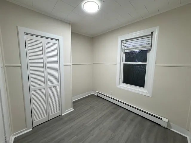 an empty room with wooden floor closet and windows