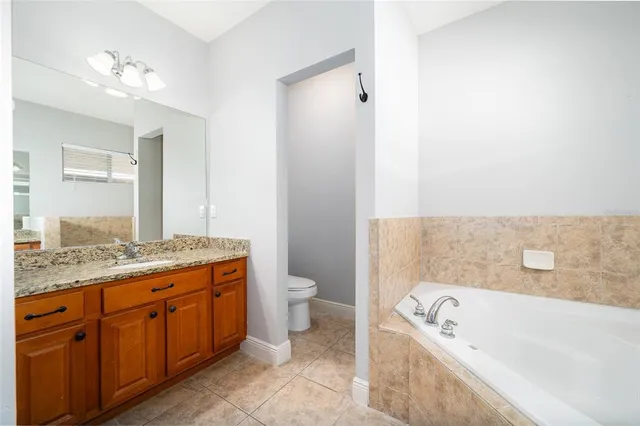 a bathroom with a granite countertop sink a toilet and bathtub
