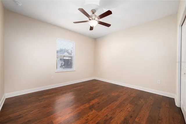 an empty room with wooden floor and ceiling fan