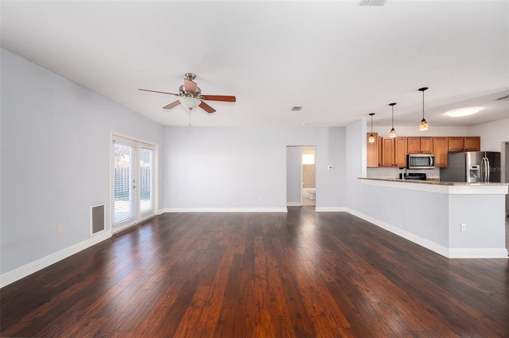 7931 Southwest 88th Street Gainesville, FL 32608 - Photo 6 of 35 a view of an empty room with wooden floor and a kitchen