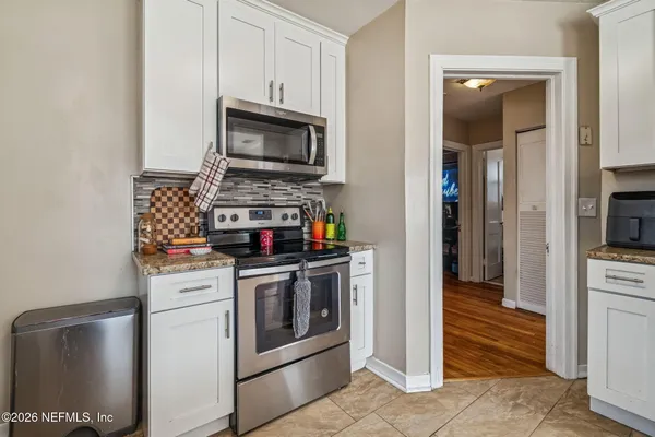 a kitchen with kitchen island granite countertop a stove top oven a sink a counter space and cabinets