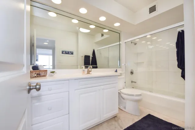 a bathroom with a double vanity sink a toilet a mirror and shower