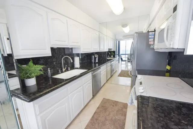 a large kitchen with stainless steel appliances kitchen island granite countertop a sink a stove and white cabinets