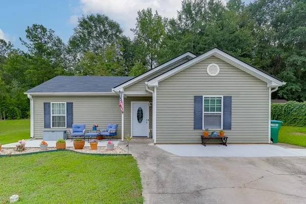 a view of a house with a yard and a large tree