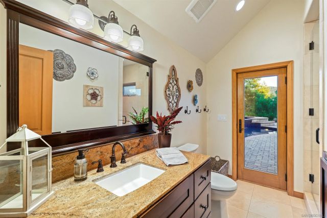 a bathroom with a granite countertop sink a mirror and shower