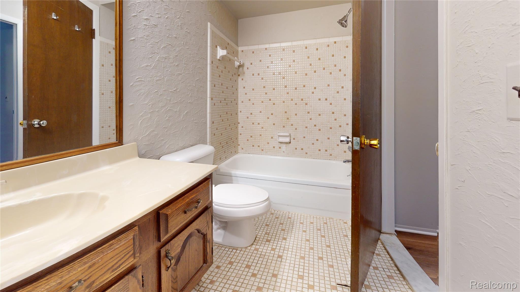 29125 Hayes Road Warren, MI 48088 - Photo 4 of 12 Bathroom featuring a vanity with a light-colored countertop and wooden cabinetry, a white toilet, and a bathtub with a shower fixture