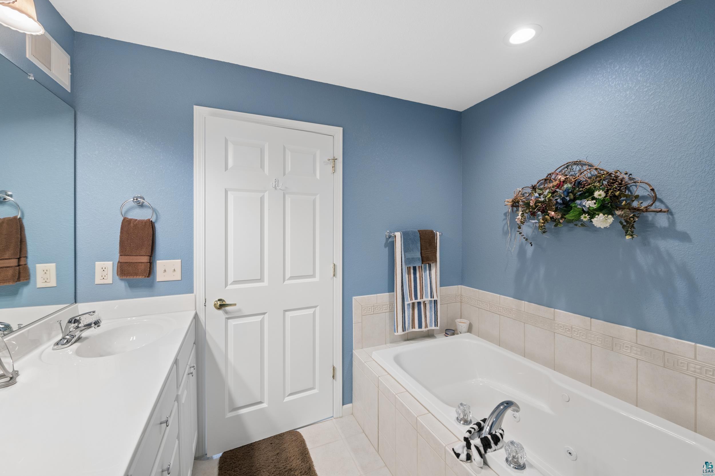 34590 Bay View Road, Unit 801 Bayfield, WI 54814 - Photo 15 of 36 Bathroom featuring a built-in bathtub with tiled surround, a white vanity with integrated sink, and an overhead recessed light