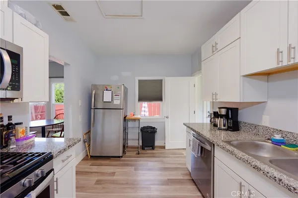 a kitchen with granite countertop a sink stainless steel appliances and cabinets