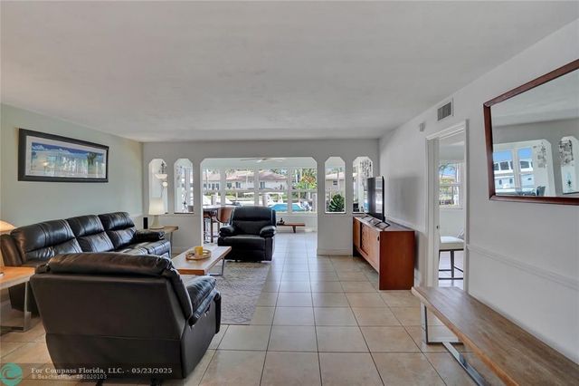 a living room with furniture a large window and kitchen view