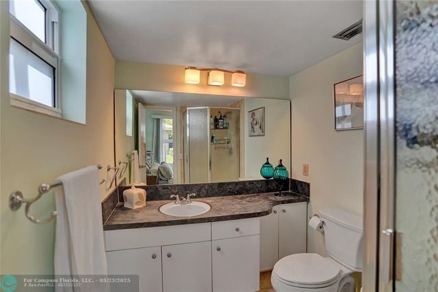 a bathroom with a granite countertop sink toilet and mirror