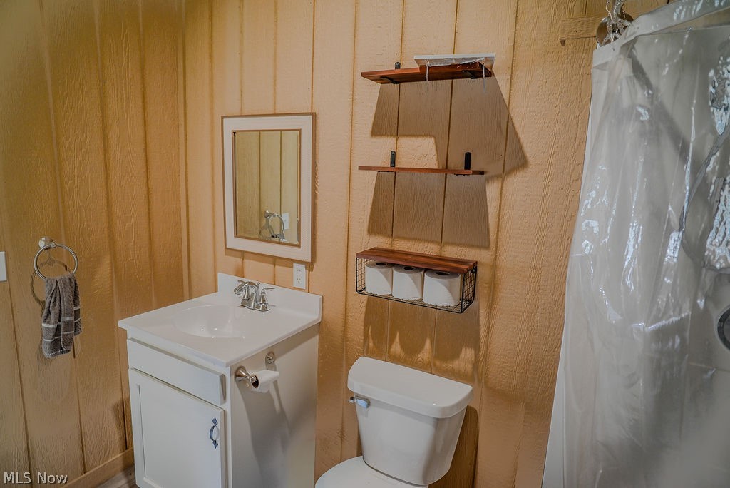 1547 Providence Road Elizabeth, WV 26143 - Photo 11 of 32 Bathroom featuring vertical wood paneling, a white vanity with an integrated sink, and a framed mirror