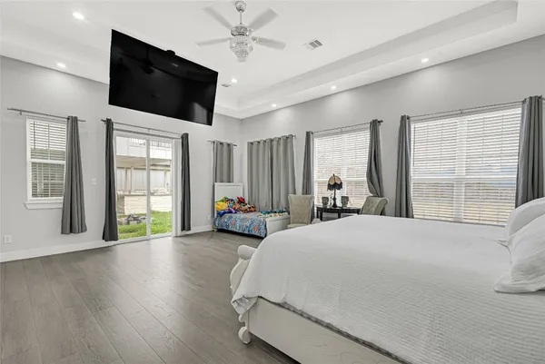 a spacious bedroom with a large bed and a flat tv screen on dresser