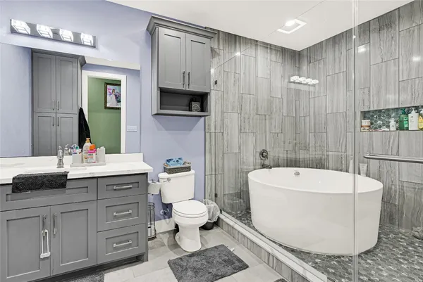 a bathroom with a double vanity sink a toilet a mirror and bathtub