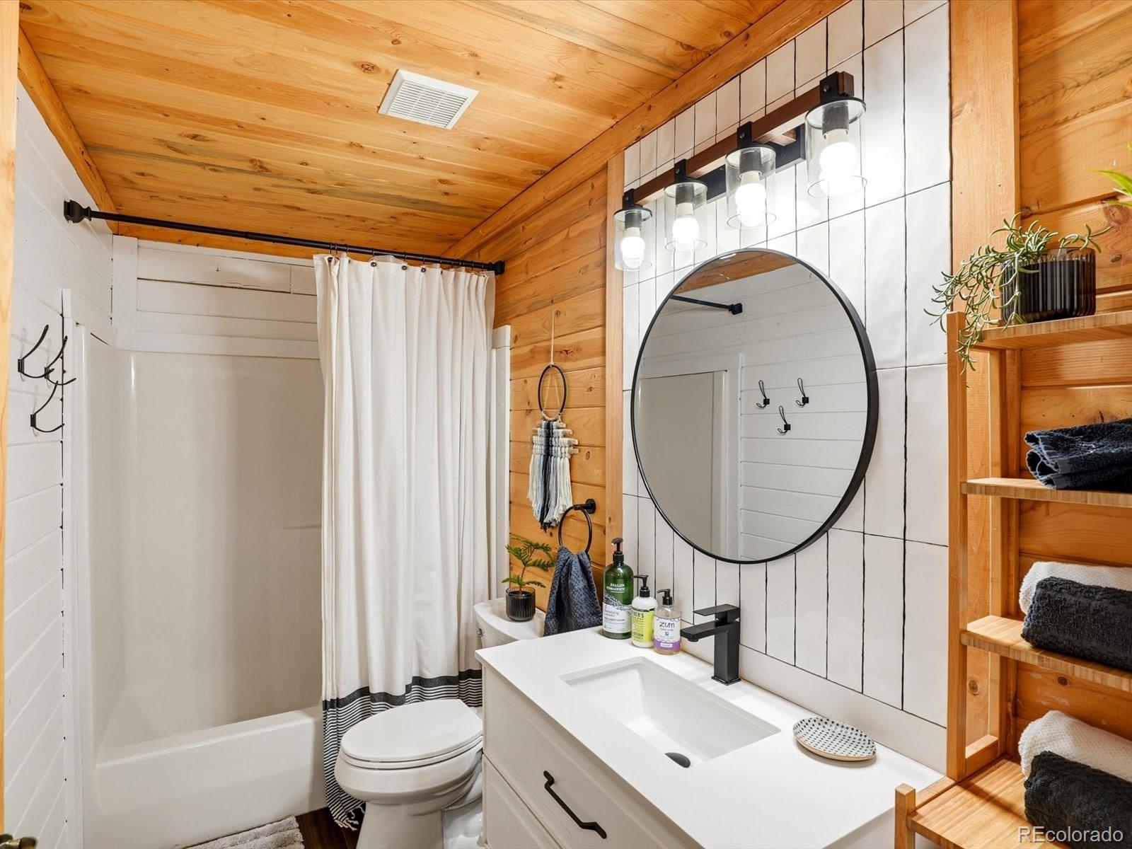 201 Moss Rock Road Bailey, CO 80421 - Photo 23 of 43 a bathroom with a sink a mirror a toilet and a window