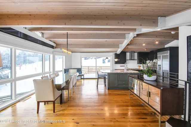 a dining hall with stainless steel appliances granite countertop a stove and a view of living room