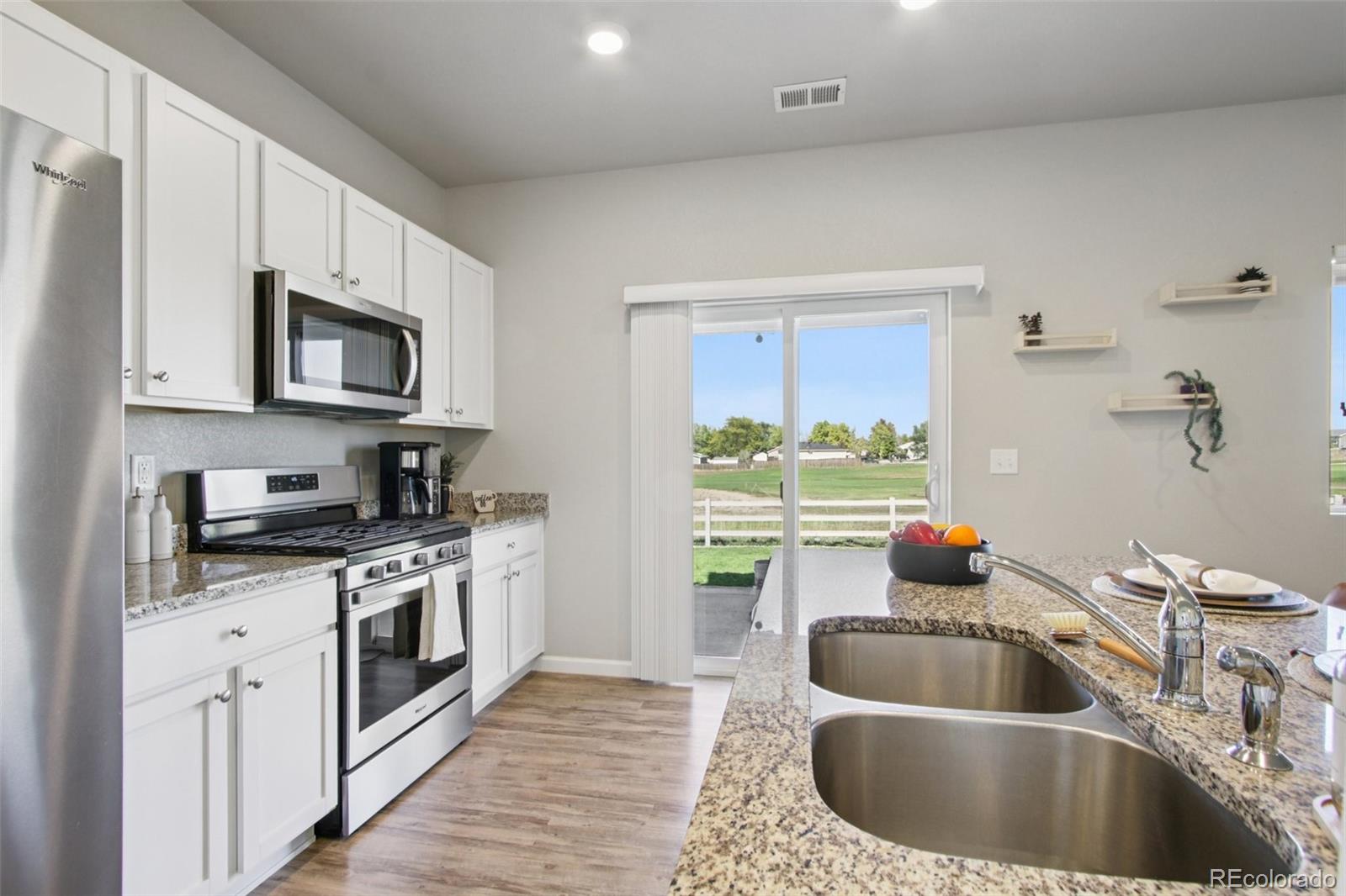 1907 Homestead Drive Fort Lupton, CO 80621 - Photo 16 of 47 a kitchen with stainless steel appliances granite countertop a sink a stove and a sink with wooden cabinets
