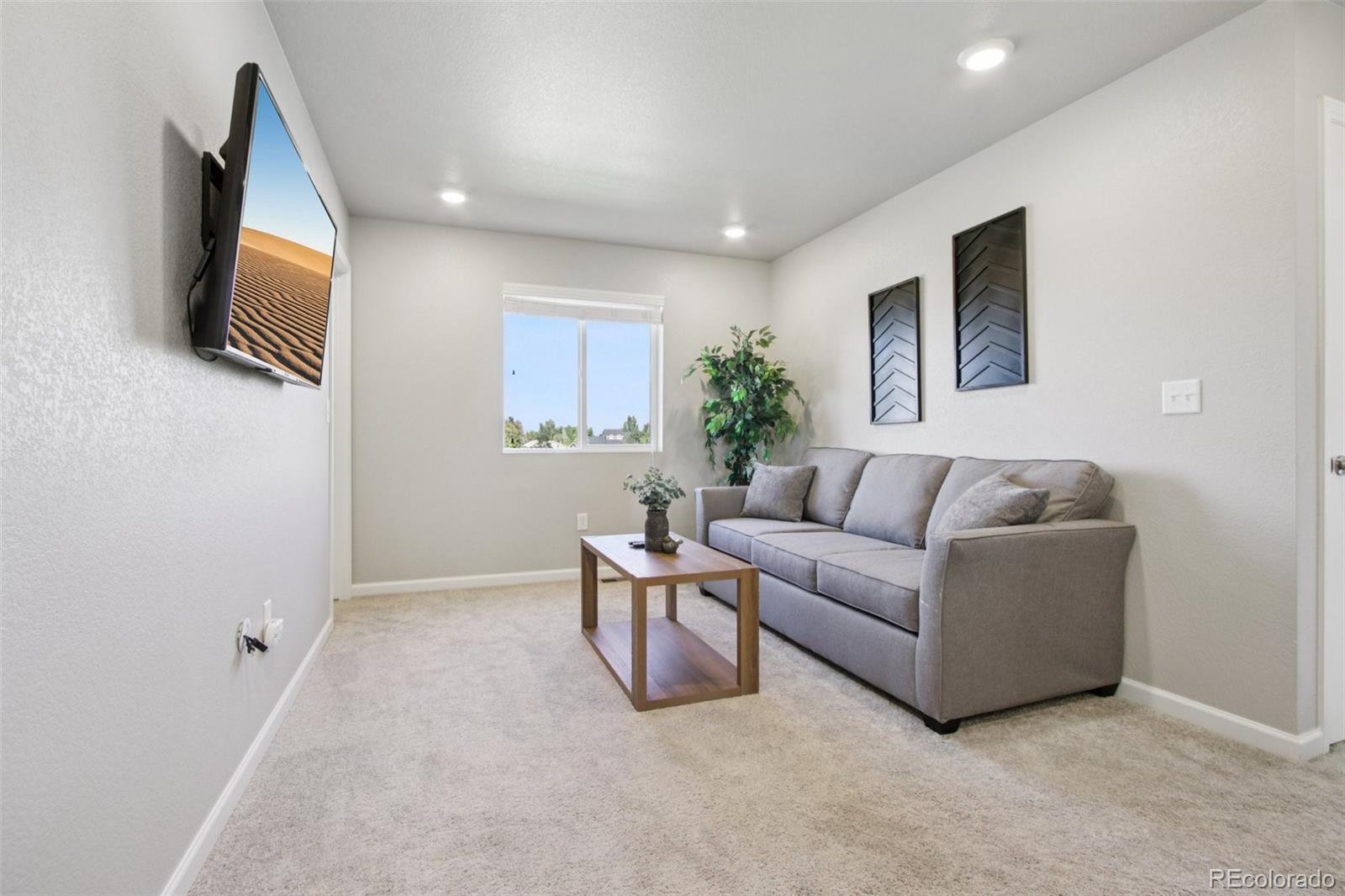 1907 Homestead Drive Fort Lupton, CO 80621 - Photo 18 of 47 a living room with furniture and a flat screen tv