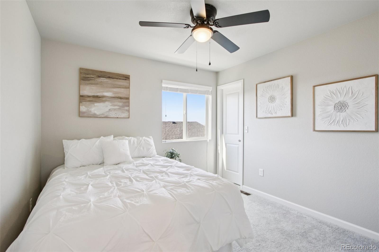 1907 Homestead Drive Fort Lupton, CO 80621 - Photo 21 of 47 a bedroom with a large bed and a ceiling fan