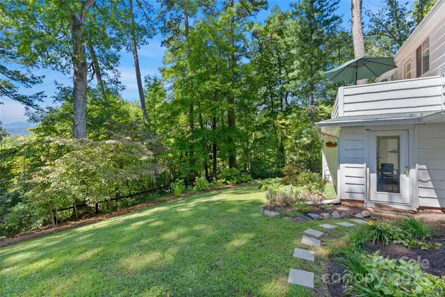 a view of a house with a yard and large tree