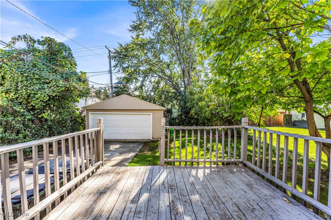 Deck featuring a garage, a lawn, and an outdoor structure