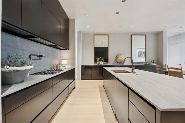 a large kitchen with stainless steel appliances a sink dishwasher a stove a microwave oven and a dining table with wooden floor