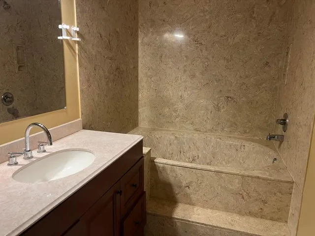 a bathroom with a granite countertop sink a toilet and shower