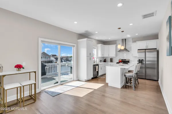a kitchen that has a lot of white cabinets and stainless steel appliances