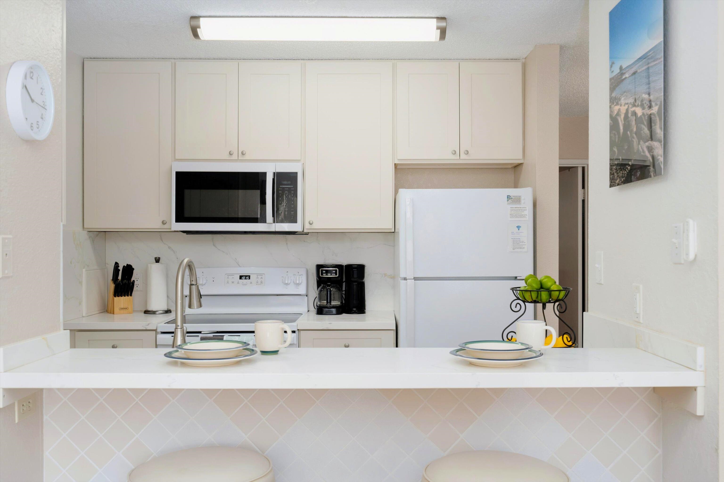 1299 Uluniu Road, Unit G104 Kihei, HI 96753 - Photo 6 of 32 a kitchen with stainless steel appliances a sink a stove a microwave a sink and white cabinets