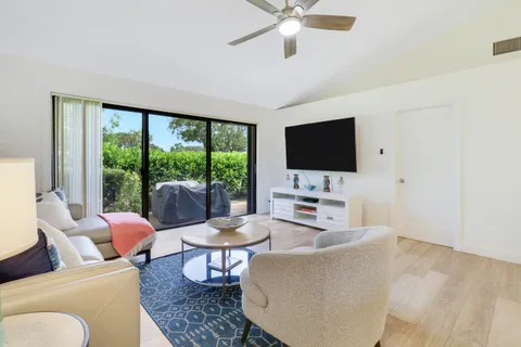 a living room with furniture a flat screen tv and a floor to ceiling window