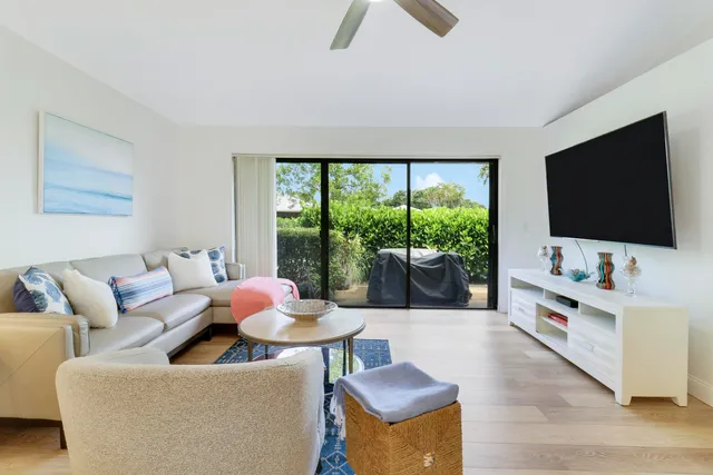 a living room with furniture a flat screen tv and floor to ceiling window
