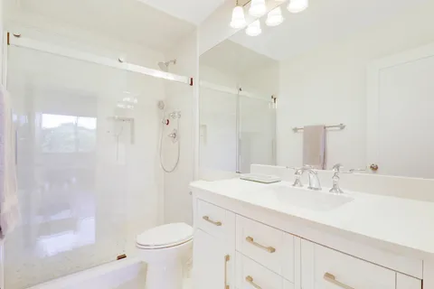 a bathroom with a sink a toilet a mirror and shower