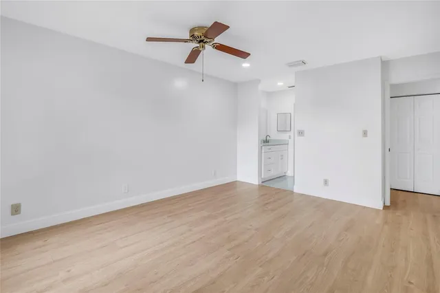 a view of empty room with wooden floor and ceiling fan