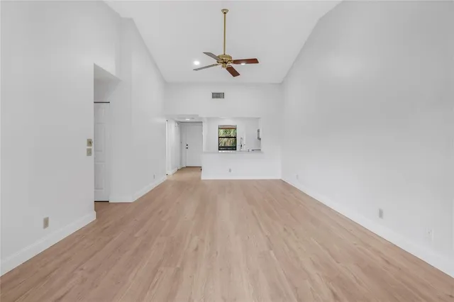 a view of empty room with wooden floor and ceiling fan