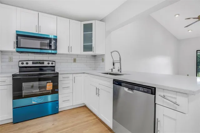 a kitchen with stainless steel appliances a stove microwave and sink