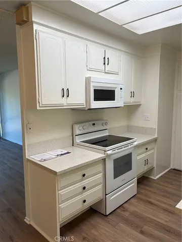 a kitchen with white cabinets stainless steel appliances and wooden floor
