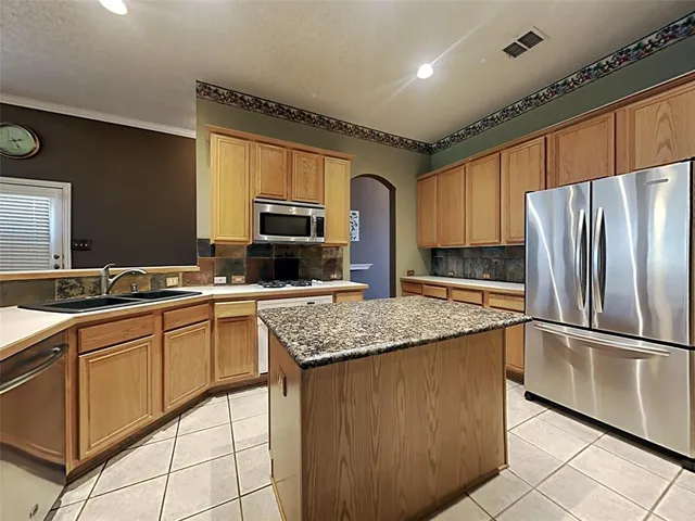 a kitchen with stainless steel appliances granite countertop a sink stove microwave and refrigerator