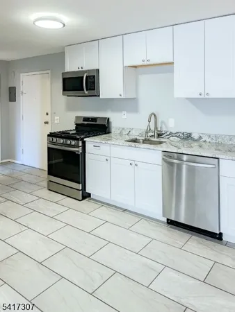 a kitchen with granite countertop a stove a sink and a microwave