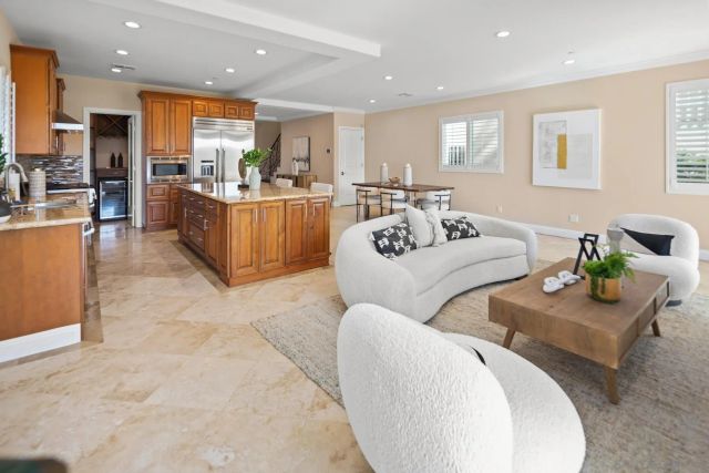 a living room with furniture kitchen view and a large window