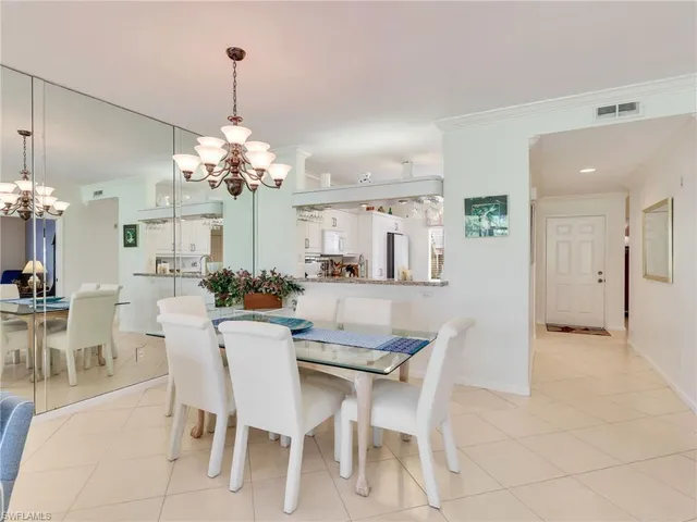 a dining room with furniture a chandelier and kitchen view
