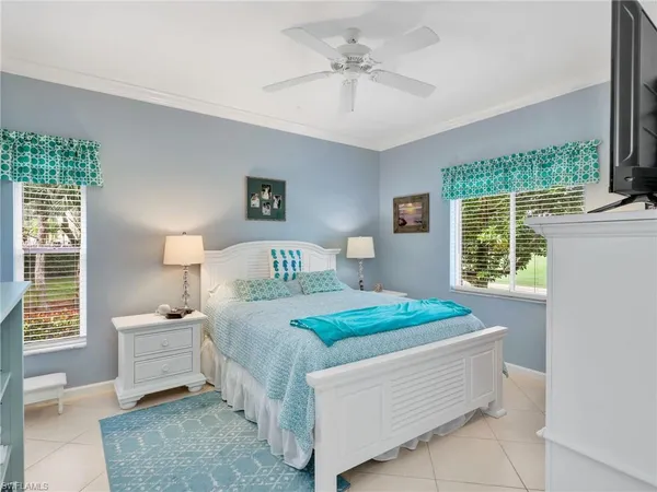 a bedroom with a bed a window and potted plant on the dresser