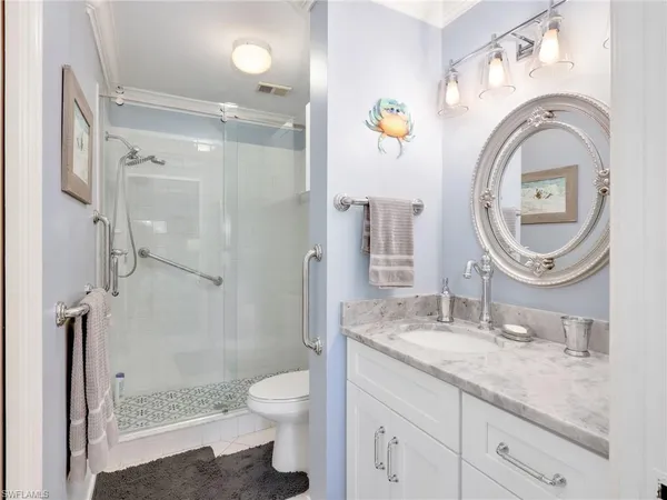 a bathroom with a granite countertop sink a mirror a toilet and a shower