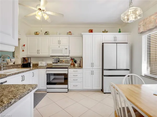 a kitchen with granite countertop white cabinets and white appliances