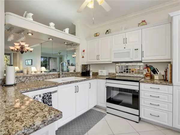 a kitchen with granite countertop white cabinets and white appliances