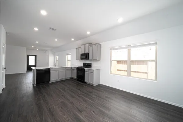 a large kitchen with a center island wooden floor stainless steel appliances and a window